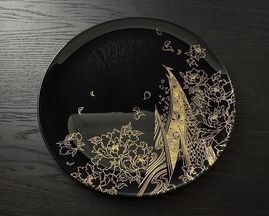 Jet black plate with a gold climbing peacock makie design, top view