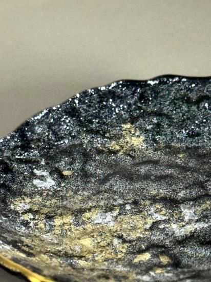 Close-up of the textured black surface with gold and silver flecks