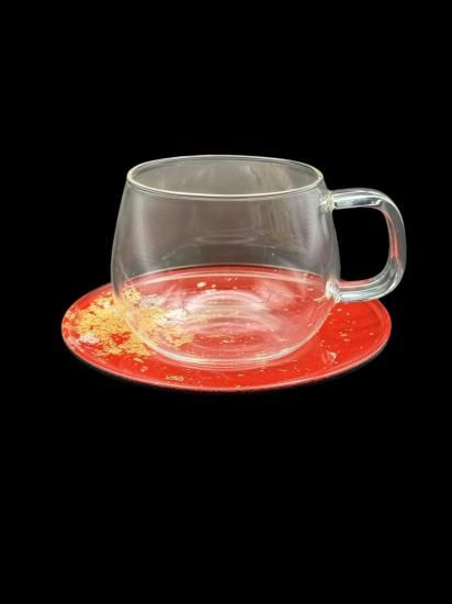 Vermilion gold leaf saucer with a clear glass cup, angled view