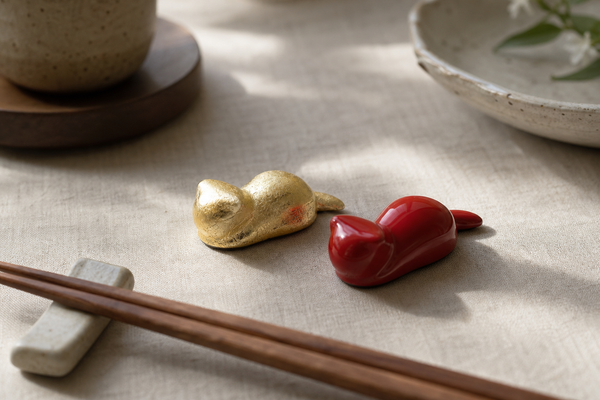 Editorial cat chopstick rests in different leaf finishes on a dining table