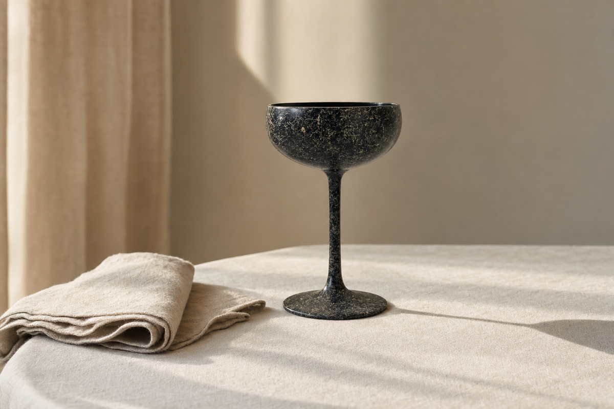 Editorial rendering of a dark Ranshi Urushi champagne saucer on a linen table