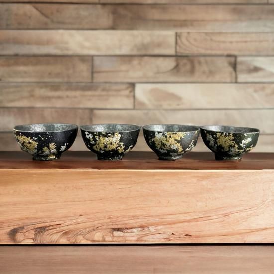 Four lacquered ceramic rice bowls in Majo Blue, Majo Green, Majo Rainbow and Tenmoku lined up on a shelf