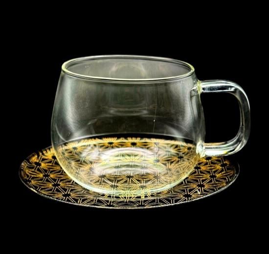 Asanoha jet black makie saucer with a clear glass cup, angled view